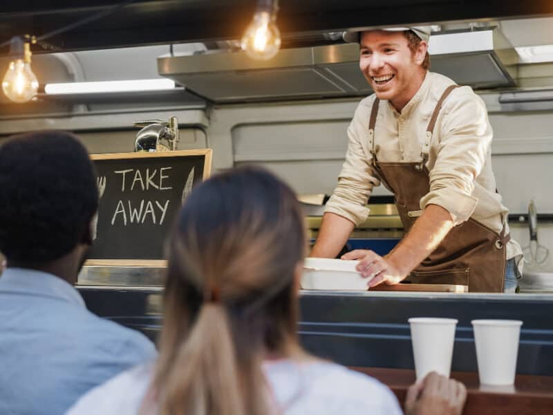 hispanischer-mann-serviert-essen-zum-mitnehmen-im-food-truck-fokus-auf-das-gesicht-des-kochs